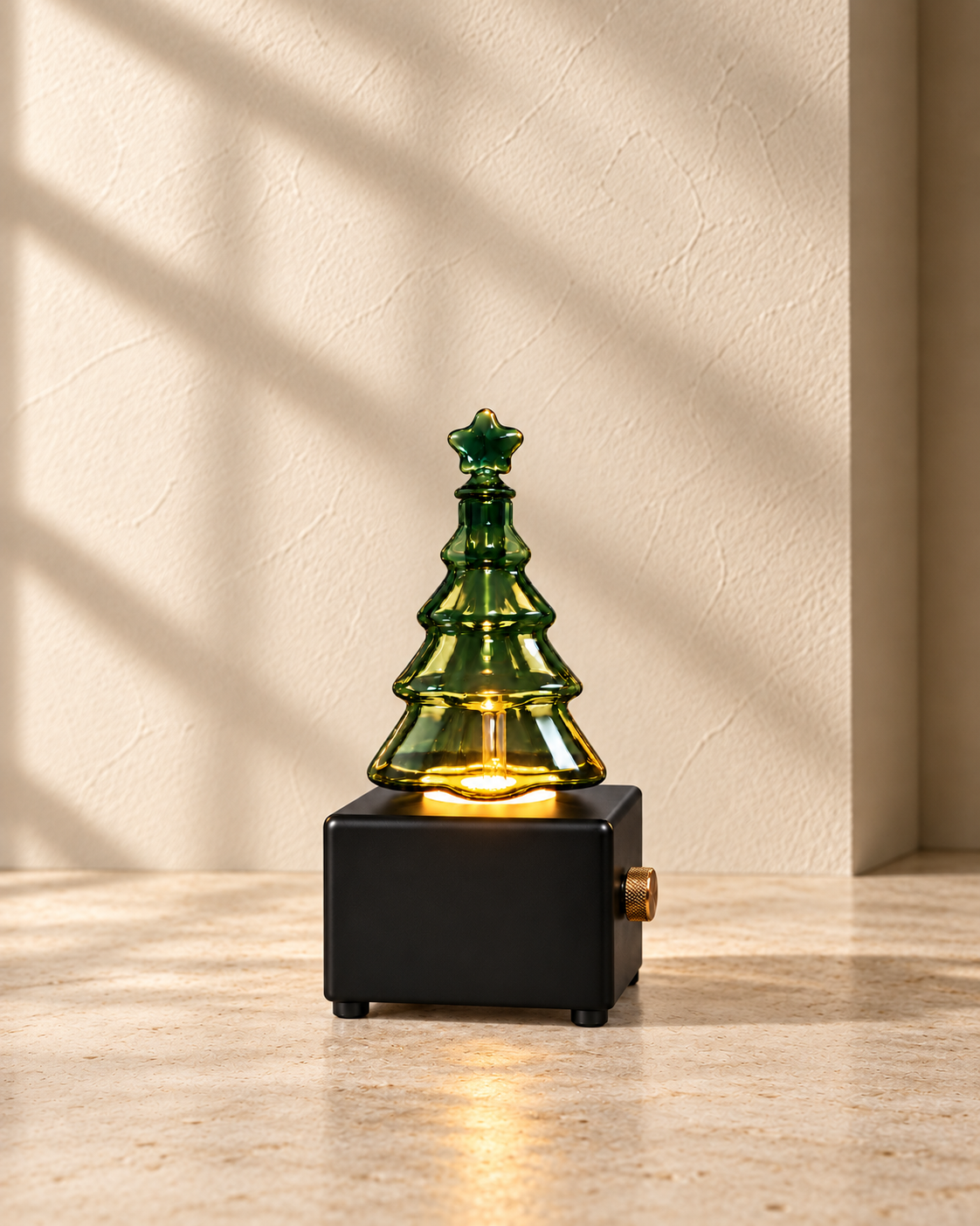 Black Christmas tree diffuser with illuminated green glass, amber light and a single brass control on the right side.