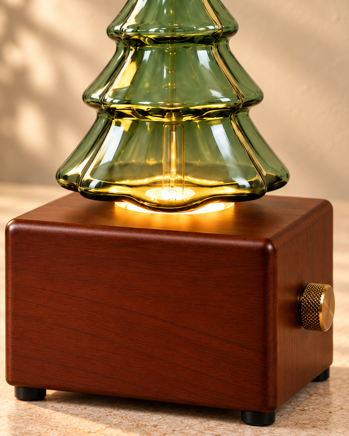 Close-up of clean green Christmas tree glass, the warm light socket and a wood-finish diffuser base.