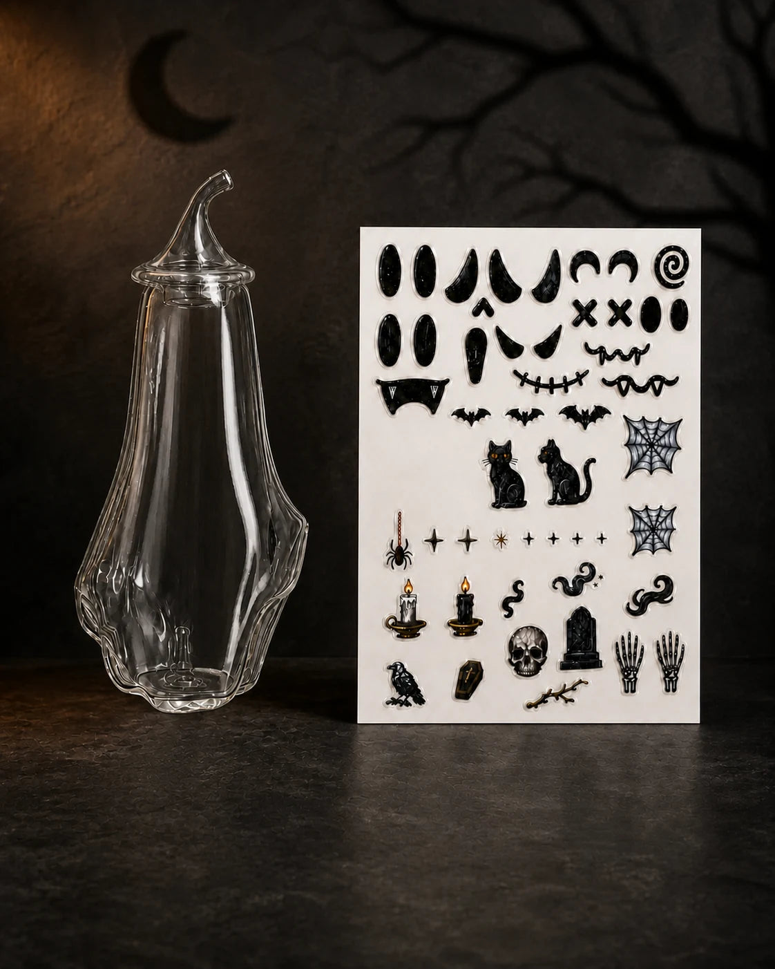 Blank ghost-shaped glass aroma bottle with its removable glass cap fitted, shown beside the complete Halloween DIY sticker sheet